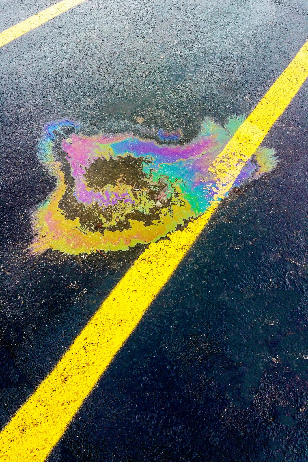 About Us Rainbow-colored oil spill on the ground, highlighting the need for spill kits in Australia.